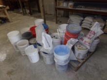 All Buckets on Floor Near Wide Shelving, Most Are Empty, Some Have Material