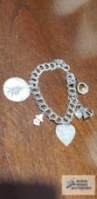 Silver colored charm bracelet marked Sterling with five charms, most marked Sterling or 925